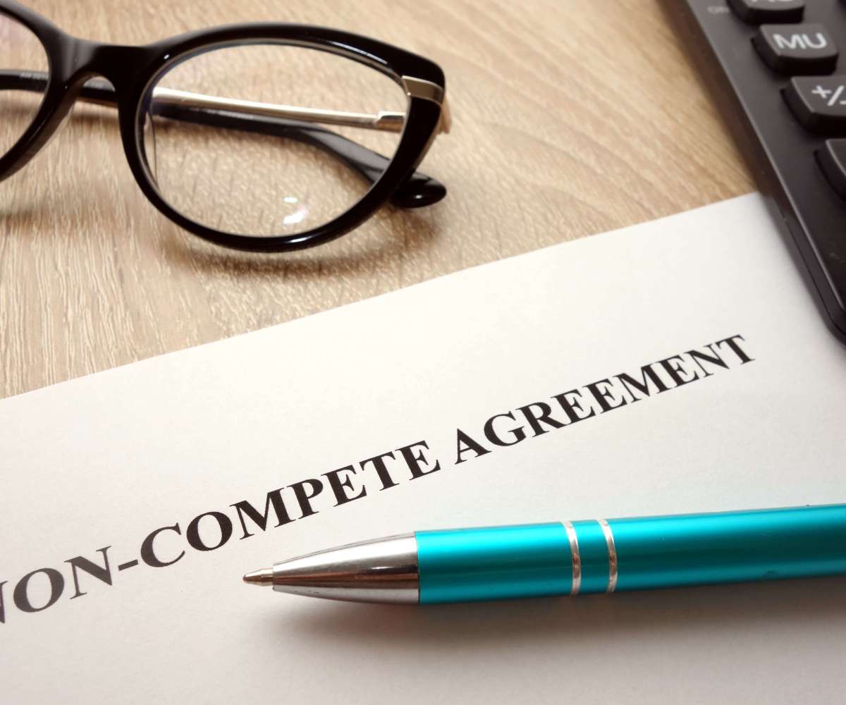 clause de non concurrence immobilier - un contrat de non-concurrence, un stylo, une paire de lunette et une calculatrice posés sur un bureau